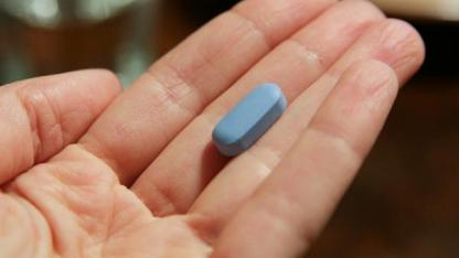 Ein Foto mit einer geöffneten Hand, in der eine blaue HIV-Tablette liegt