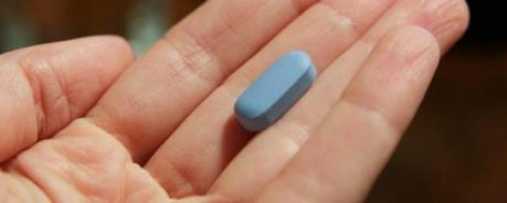 Ein Foto mit einer geöffneten Hand, in der eine blaue HIV-Tablette liegt